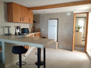 Een moderne keuken met houten kastjes, een witte koelkast, een spoelbak en een eethoek met een tafel en stoelen.