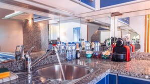 A modern kitchen with a stainless steel sink, a coffee machine, and various bottles. - Bissone   Campione Lake Pool & Relax (Bissone)