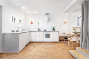 Eine moderne Küche mit weißen Schränken, einer zentralen Kochinsel und einem Essbereich mit Tisch und Stühlen.