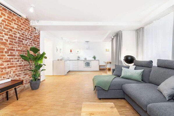 Ein modernes Wohnzimmer mit einem grauen Sofa, einem Holztisch und einer Ziegelwand.