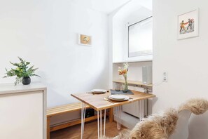 Eine kleine, moderne Küche mit einem Holztisch, weißen Wänden und einer kleinen Pflanze.