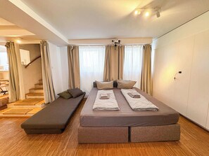 Ein modernes Schlafzimmer mit einem großen Bett, einer Sitzbank und einer Treppe, die zu einer erhöhten Ebene führt.
