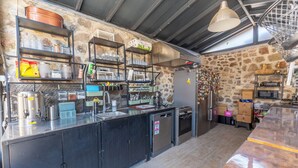 Une cuisine équipée d’appareils électroménagers en acier inoxydable, de rayonnages remplis de vaisselle et d’un mur en pierre.
