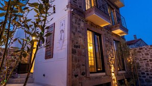 Un immeuble à plusieurs étages, doté d’une façade en pierre, d’un balcon et d’un escalier menant à l’entrée.