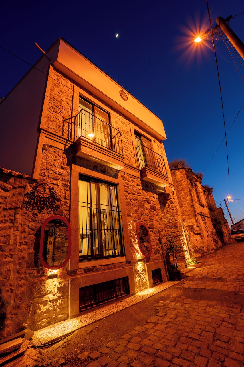 A stone building with a balcony, a large window, and a street lamp.