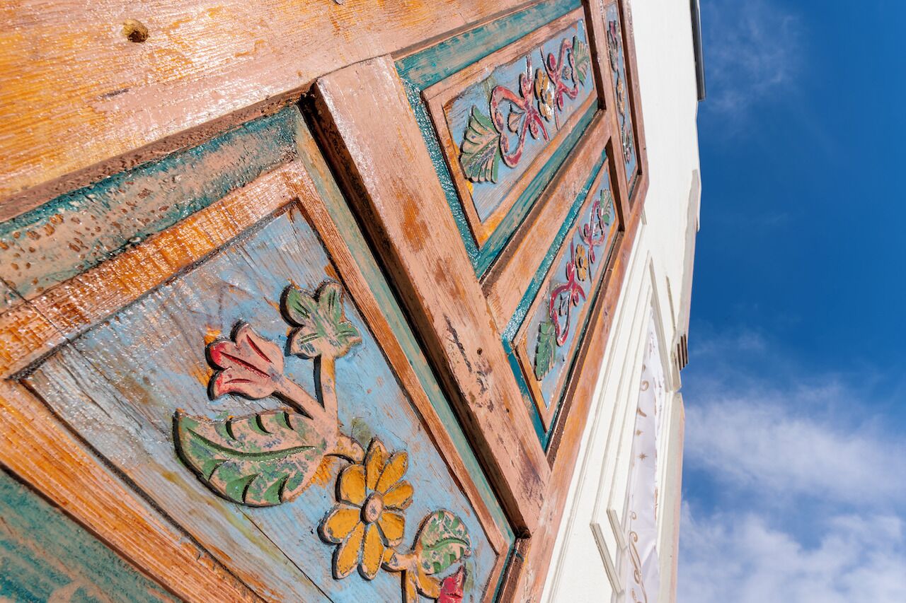 A close-up of a weathered wooden door with floral carvings.