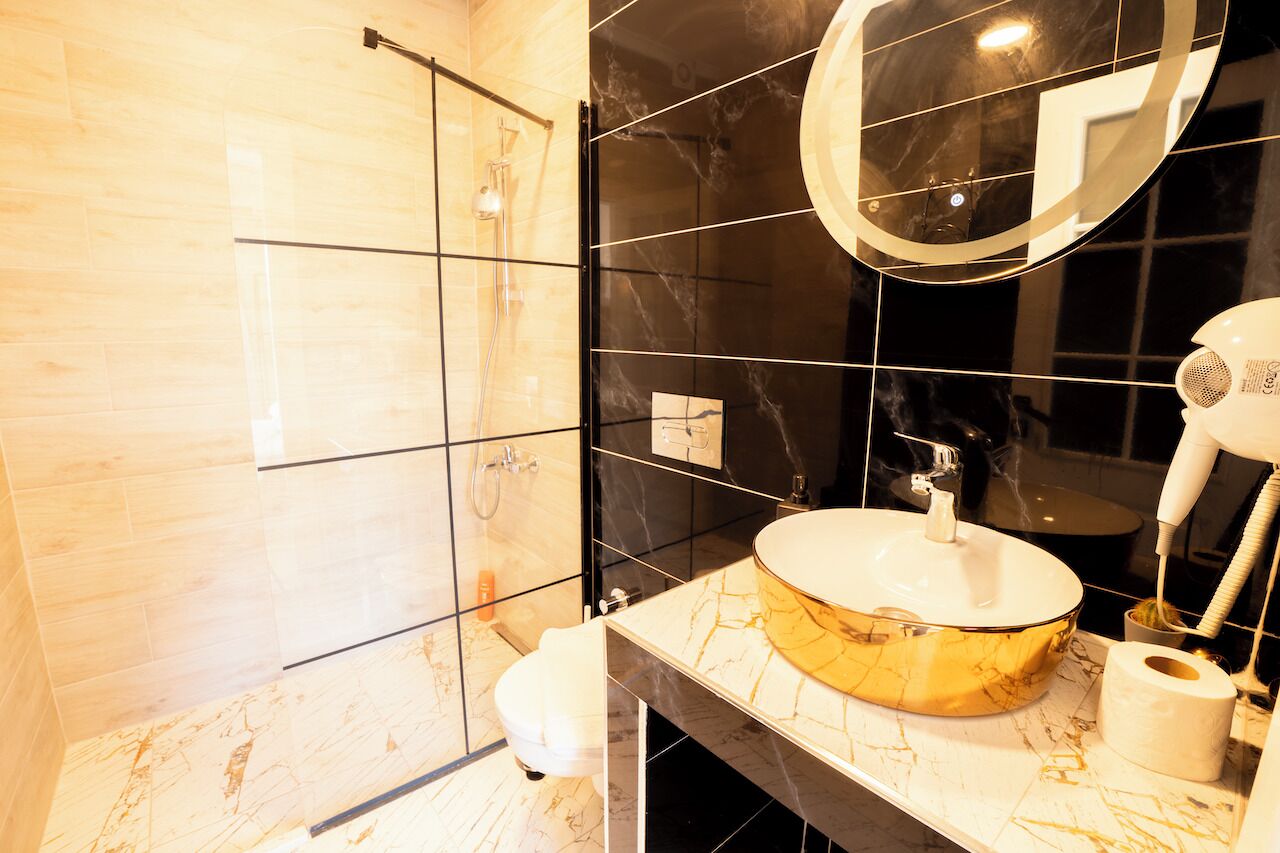 A modern bathroom with a glass shower enclosure, a marble vanity, and a large mirror.