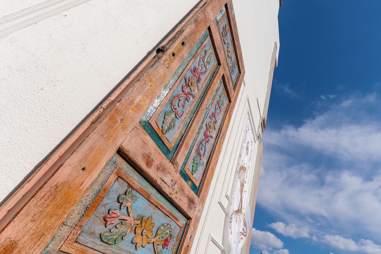 A corner of a building with decorative wooden panels and a white wall.