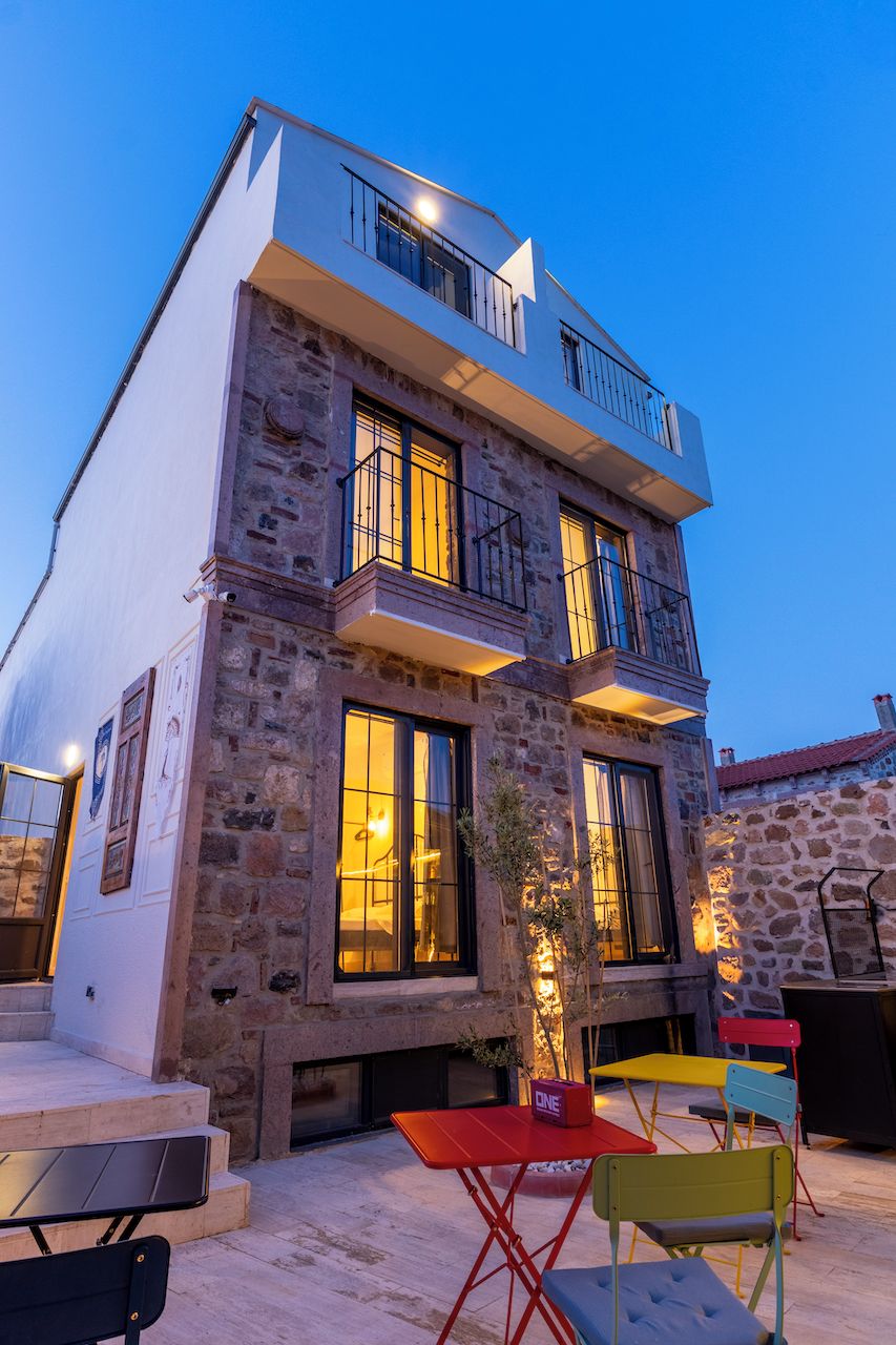 A multi-story building with stone facade, balconies, and outdoor seating.