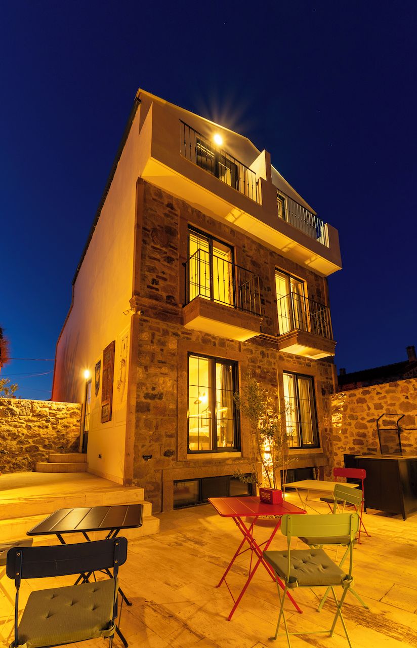 A two-story building with a stone facade, multiple windows, and a balcony.