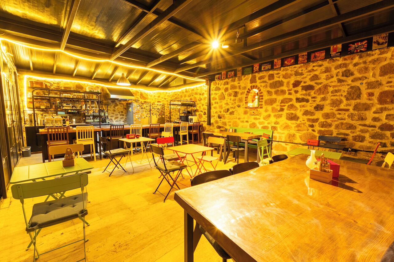 A restaurant with a stone wall, wooden tables, and chairs.