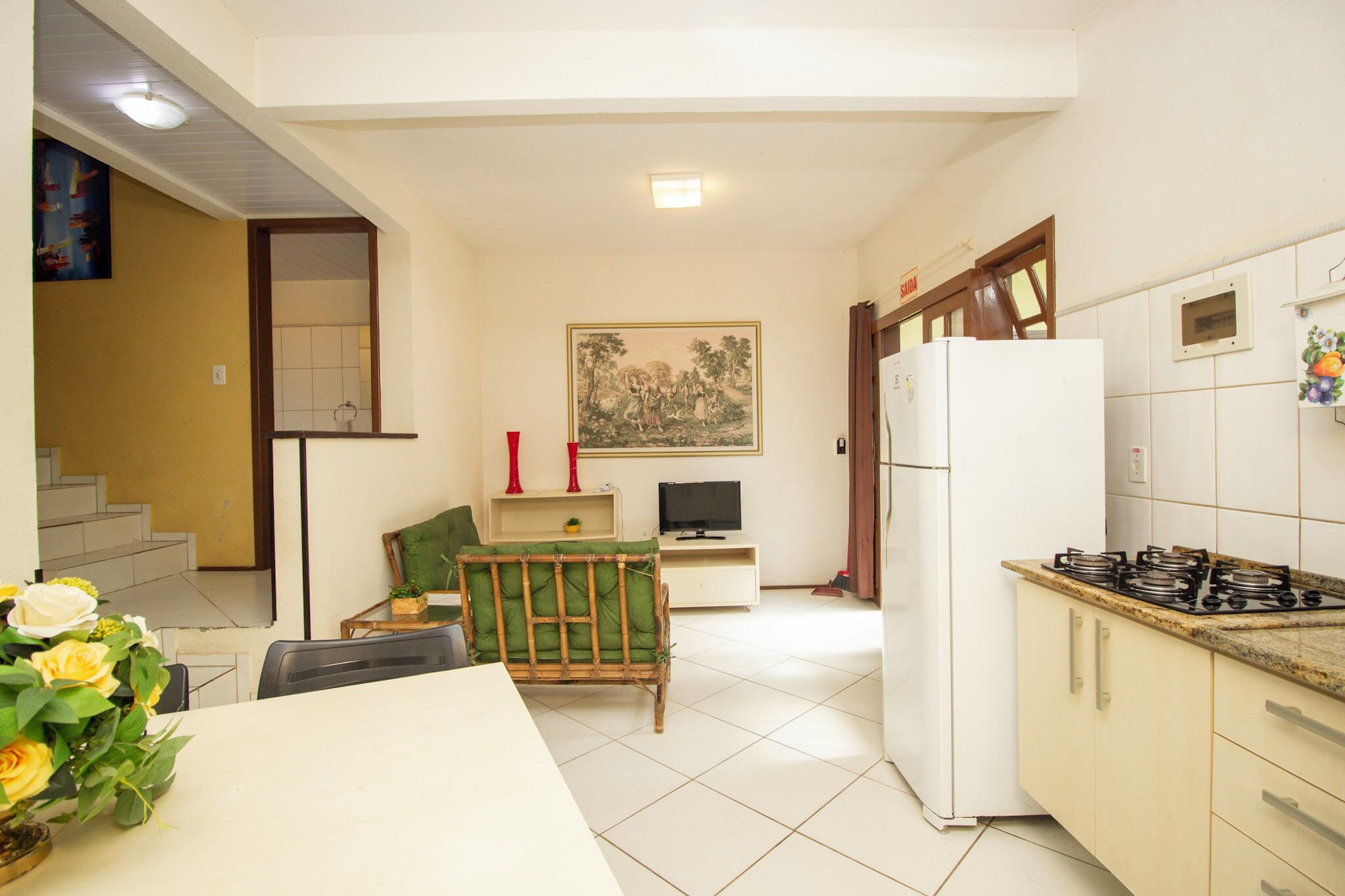 A compact kitchen with a refrigerator, stove, and dining area with a table and chairs.