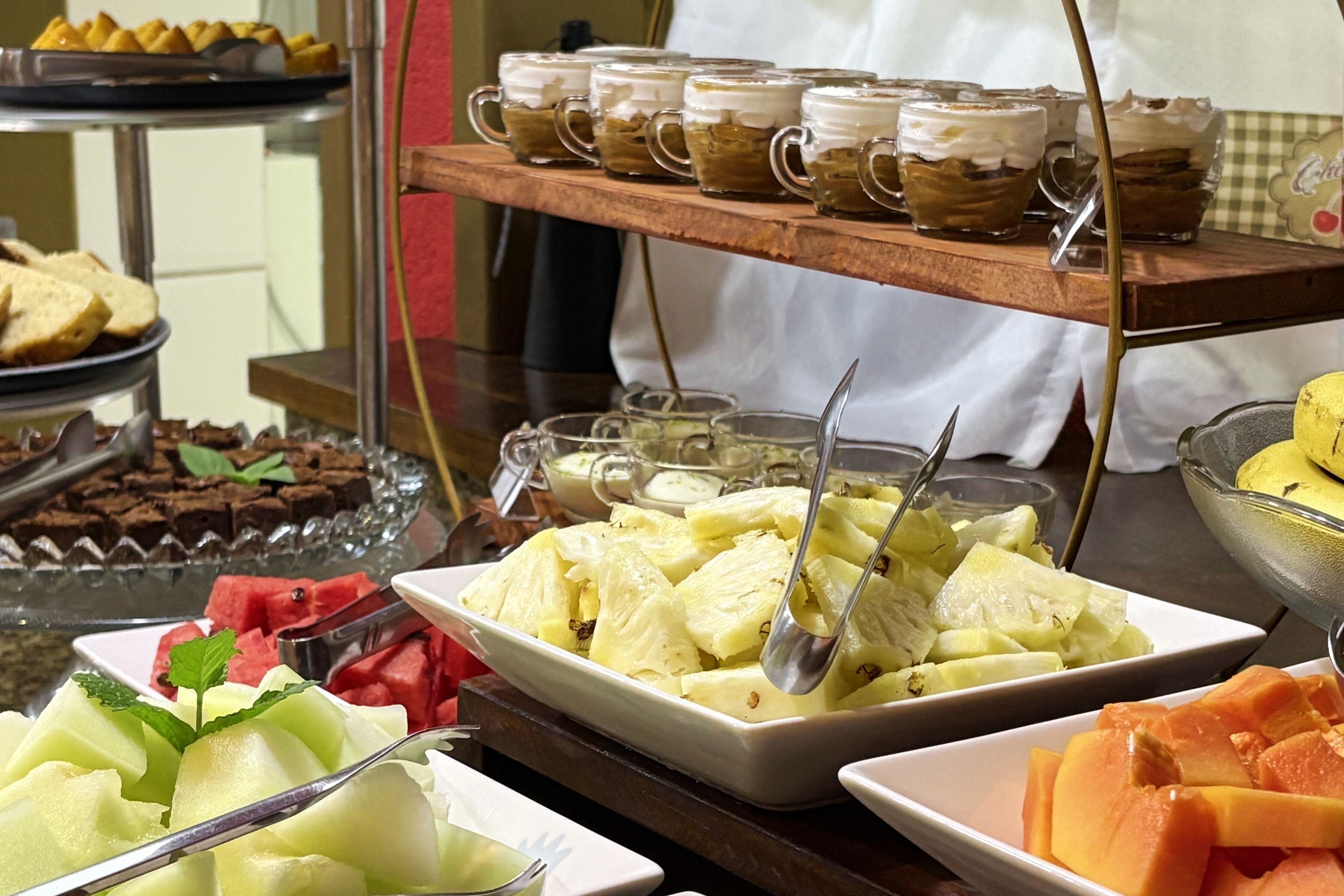 A buffet with various food items including fruits, desserts, and beverages.