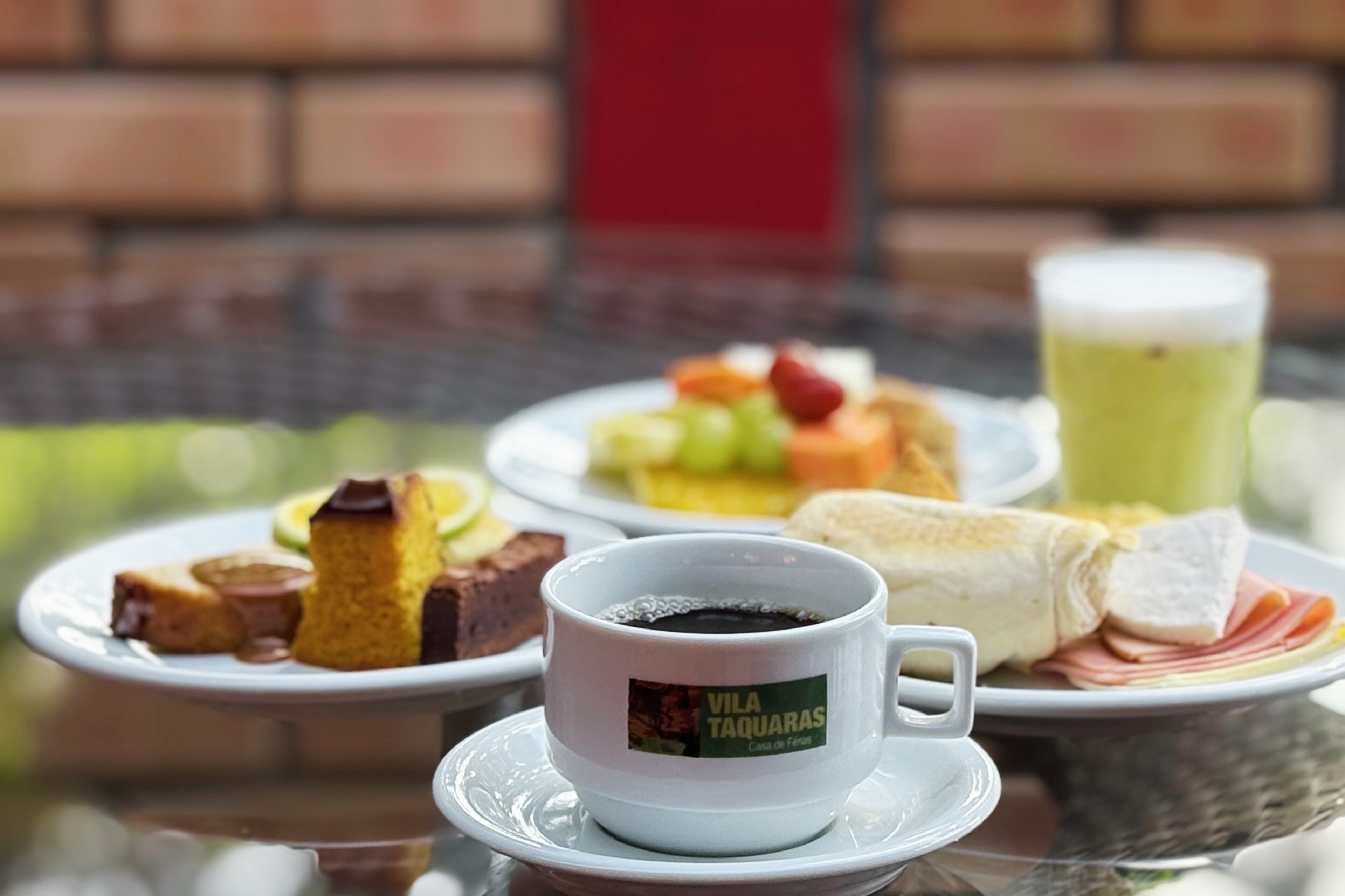 A table with plates of food, a cup of coffee, and a glass of beverage.