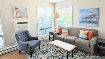 A living room with a grey sofa, a blue armchair, a wooden coffee table, and a patterned rug.