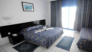 Ein Hotelzimmer mit einem Bett, einem Nachttisch, Vorhängen vor einem Fenster und einem Wandbild.
