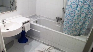Ein Badezimmer mit weißem Waschbecken, einer Badewanne und einer Duschvorhang.