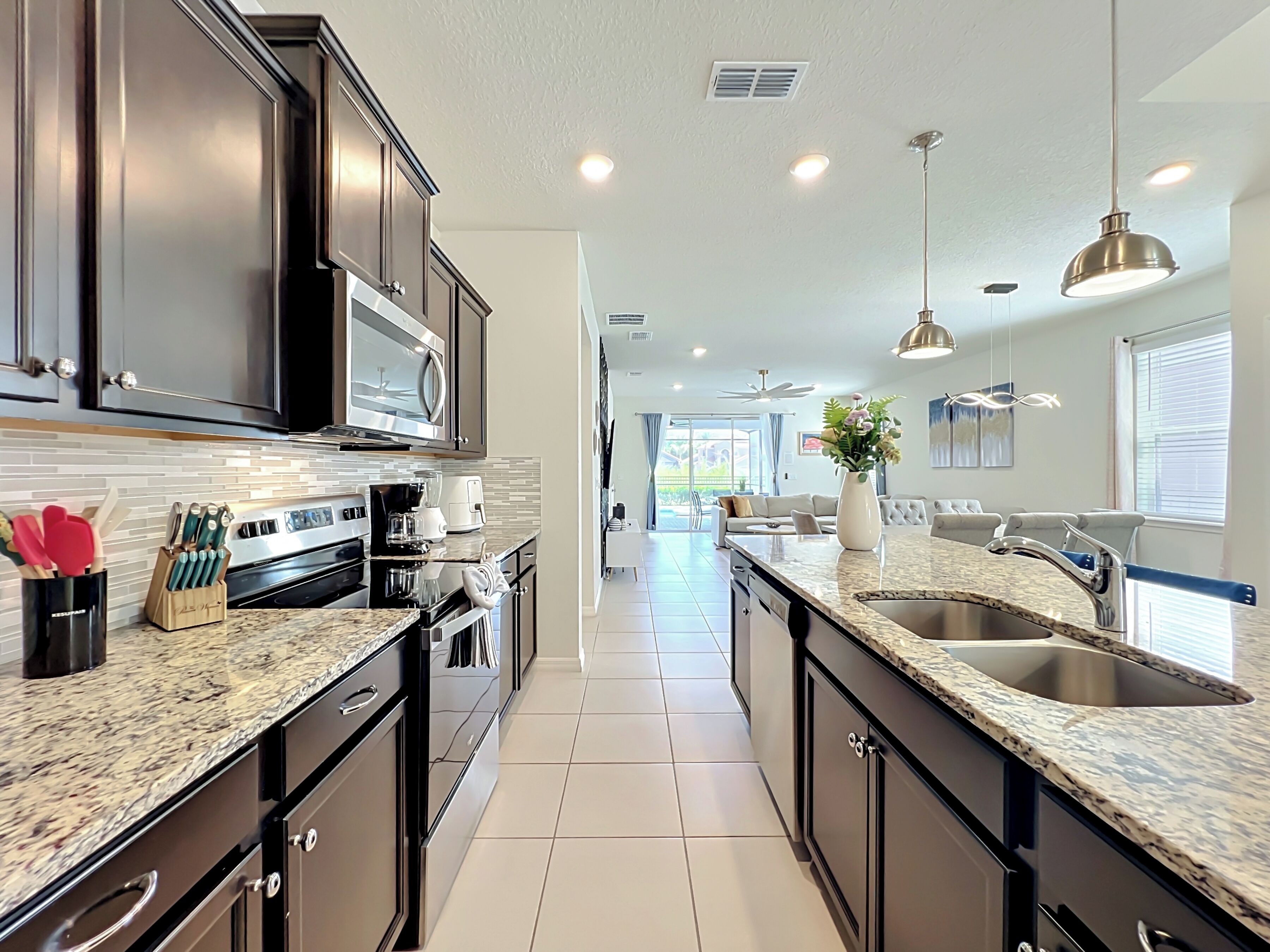 A modern kitchen with dark cabinets, stainless steel appliances, and a large island with a sink.