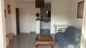 Ein Wohnzimmer mit einer Couch, einem Couchtisch und einer Küche im Hintergrund.