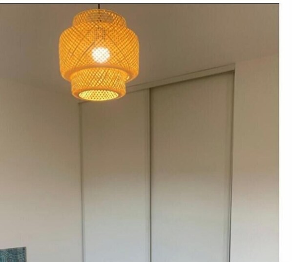 A room with a hanging woven light fixture and a closed sliding door. - Beautiful apartment 500 m from the Arcachon basin (Lanton)