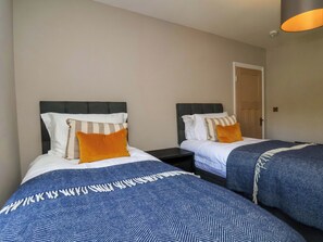 Ein Hotelzimmer mit zwei Betten, jeweils mit Kopfteil, Nachttisch und Lampe.