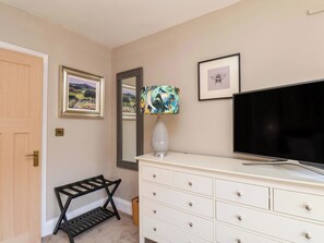 A bedroom with a bed, a dresser, a TV, a lamp, a mirror, and framed pictures on the wall. - 16 High Street (Scarborough)