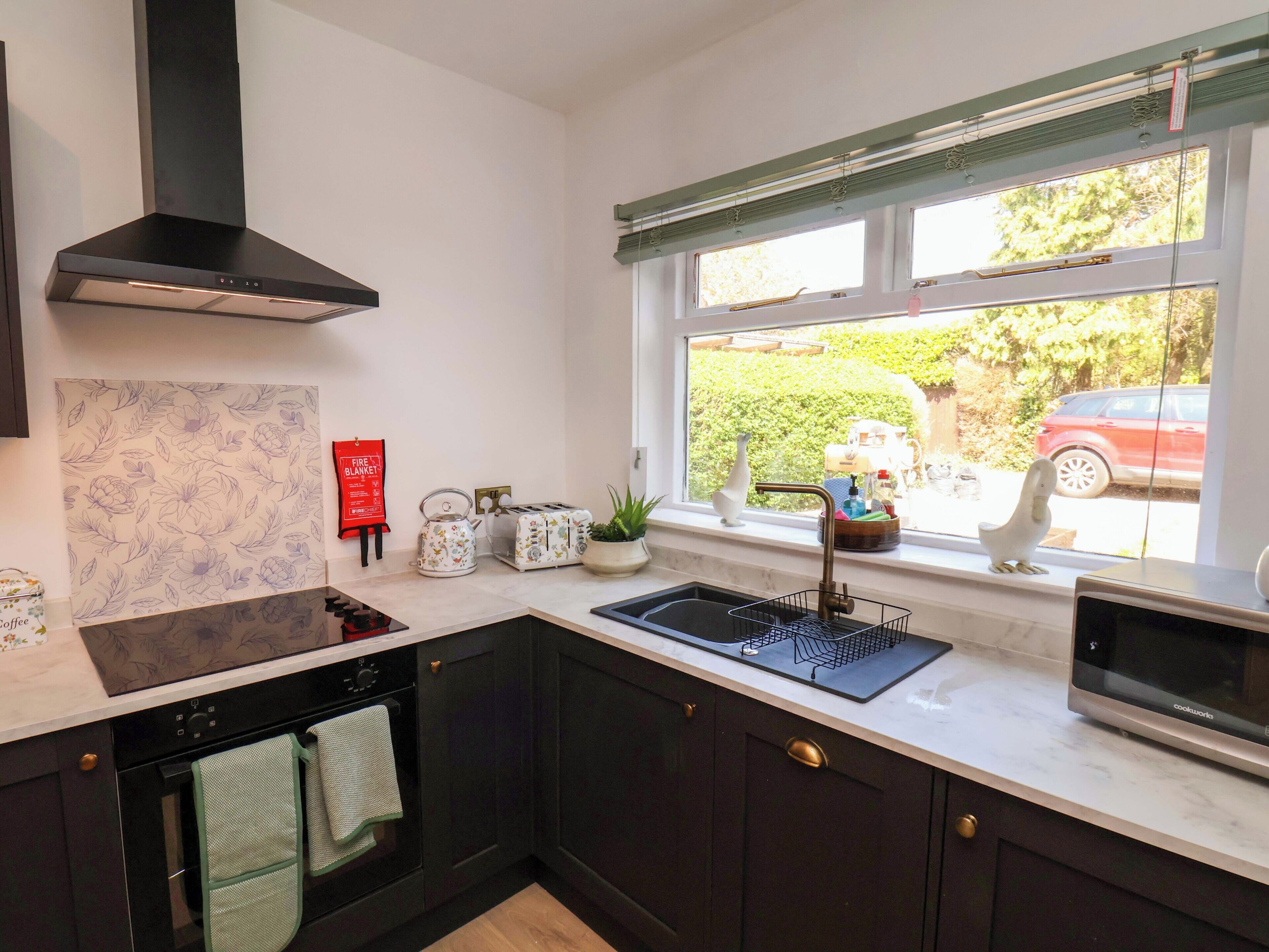A kitchen with a stove, oven, microwave, and a window with a view of the outside.