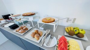 Un bufé con diferentes opciones de comida, incluyendo pasteles, frutas y un pastel.