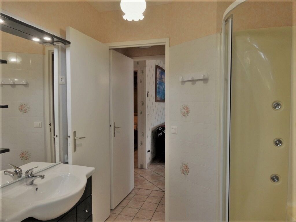 Une salle de bain avec un lavabo blanc, un miroir et un espace douche.