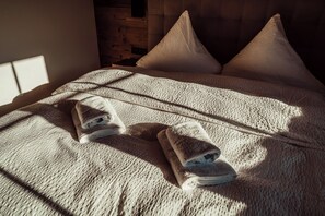 A bed with a textured blanket and two rolled towels. - Forestum - Black Forest Luxury Apartments - Apartment Rothirsch with sauna (Sankt Blasien)