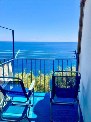 Ein Balkon mit zwei Stühlen, einem Geländer und Blick aufs Meer.