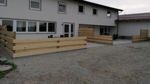 A building with multiple windows, a gravel courtyard, and wooden fences. - Holiday Home 'Island Pferdehof Arrisholt Solskin' with Private Terrace, Shared Garden & Wi-Fi (Kißlegg)