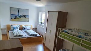 A room with a bunk bed, a single bed, a wardrobe, a painting of a lighthouse, and a window with a view. - Holiday Home 'Island Pferdehof Arrisholt Solskin' with Private Terrace, Shared Garden & Wi-Fi (Kißlegg)