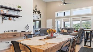 A modern dining area with a wooden table, chairs, and a coffee bar. - Modern Table Rock Lake Retreat | Swim Dock + Pool (Reeds Spring)