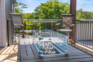 A glass fire pit on a wooden deck with chairs and a railing. - Modern Table Rock Lake Retreat | Swim Dock + Pool (Reeds Spring)