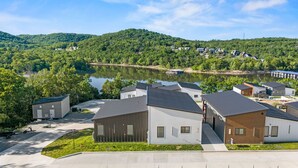 A residential area with houses, a lake, and hills in the background. - Modern Table Rock Lake Retreat | Swim Dock + Pool (Reeds Spring)