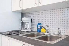 A kitchen with two stainless steel sinks, a coffee maker, and a bottle of dish soap. - The Purple Pelican~Beachfront w/ Ocean Balcony~#5 (Fort Lauderdale)