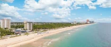 A coastal view with a beach, buildings, and clear skies.