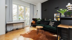 A modern living room with a green sofa, a wooden coffee table, a radiator, and a large window with curtains. - ShortStayPoland Orla B61 (Warsaw)
