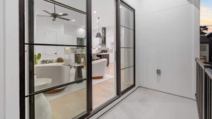 Un interno moderno con una parete divisoria in vetro, una ventola a soffitto e una zona pranzo visibile attraverso il vetro.