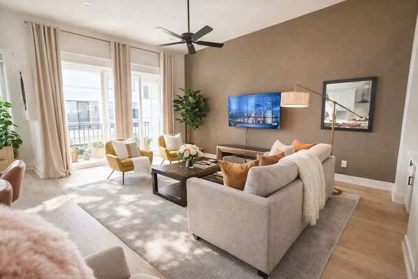 A modern living room with a sofa, coffee table, and a television mounted on the wall. - Sunhaven Rooftop Villa Gated Retreat with Terrace (Houston)