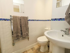Ein Badezimmer mit Toilette, Waschbecken, Handtuchhalter und einer blauen Fliesenspiegel.