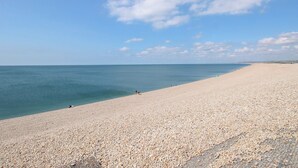 A wide, pebbled beach with a clear sky and calm sea. - Seaview Portland (Portland)