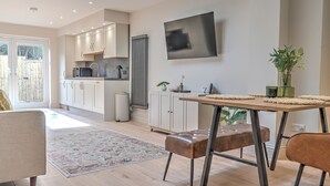 Una cucina moderna con mobili bianchi, un'ampia finestra e un'area pranzo con tavolo e sedie.