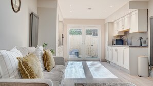 Una cucina moderna con mobili bianchi, un forno a microonde integrato e un cestino per i rifiuti.