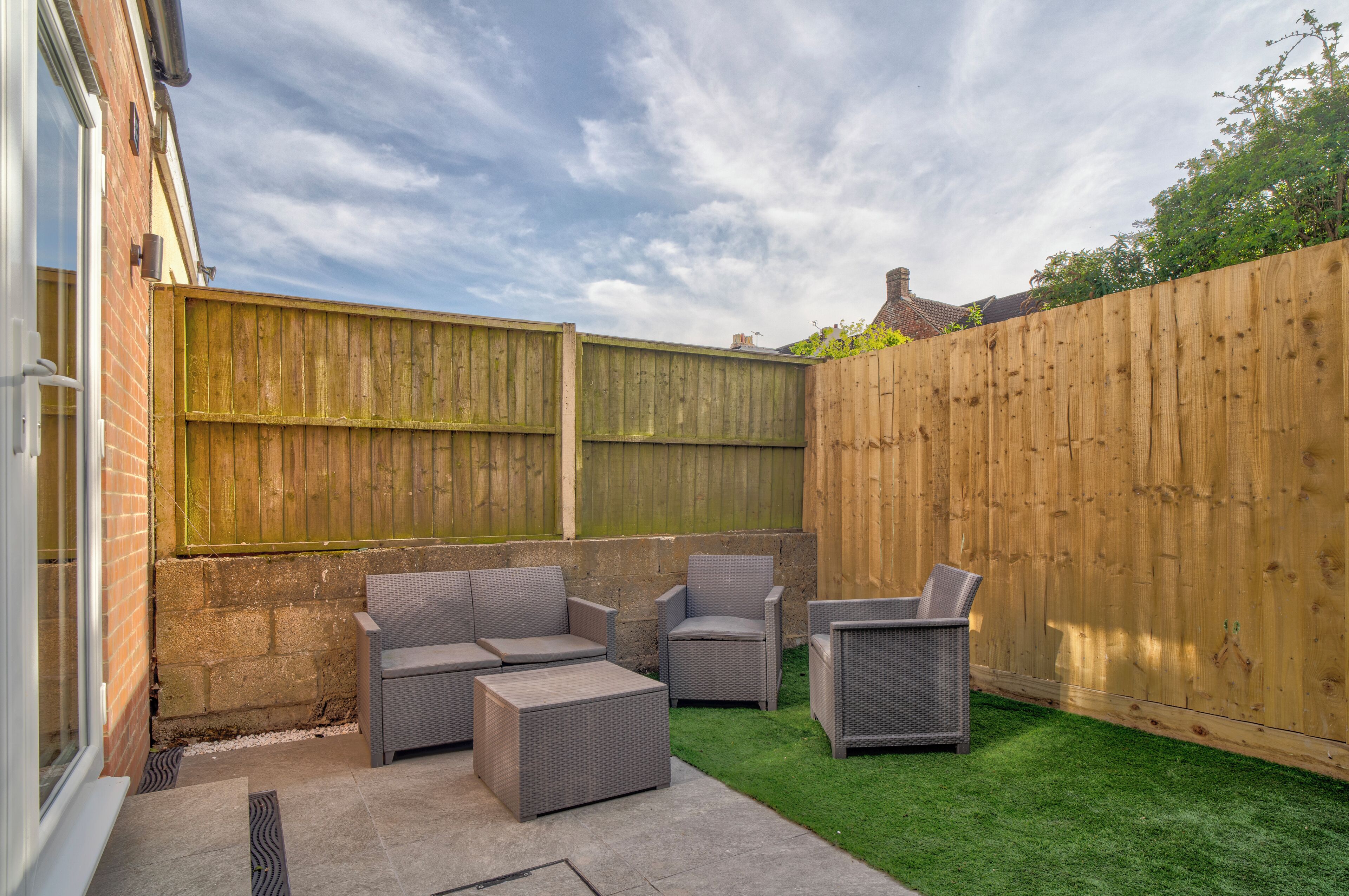 A patio with wicker furniture, a brick wall, and a wooden fence.