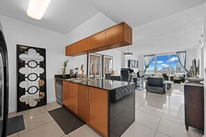 Eine moderne Küche mit Kochinsel, Holzschränken und einem Essbereich mit Sofa und Tisch.