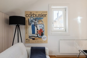 Una habitación con un cartel en la pared, una lámpara, una ventana y un radiador.