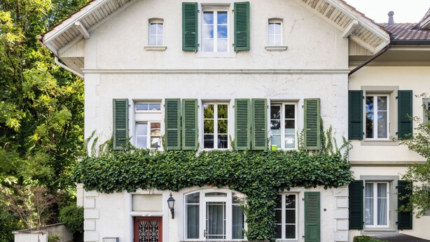 A two-story building with a symmetrical facade, green shutters, and a central entrance with a decorative door. - Art Apartments Bern (Bern)