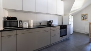 A modern kitchen with white cabinets, a black countertop, and a built-in oven. - Art Apartments Bern (Bern)